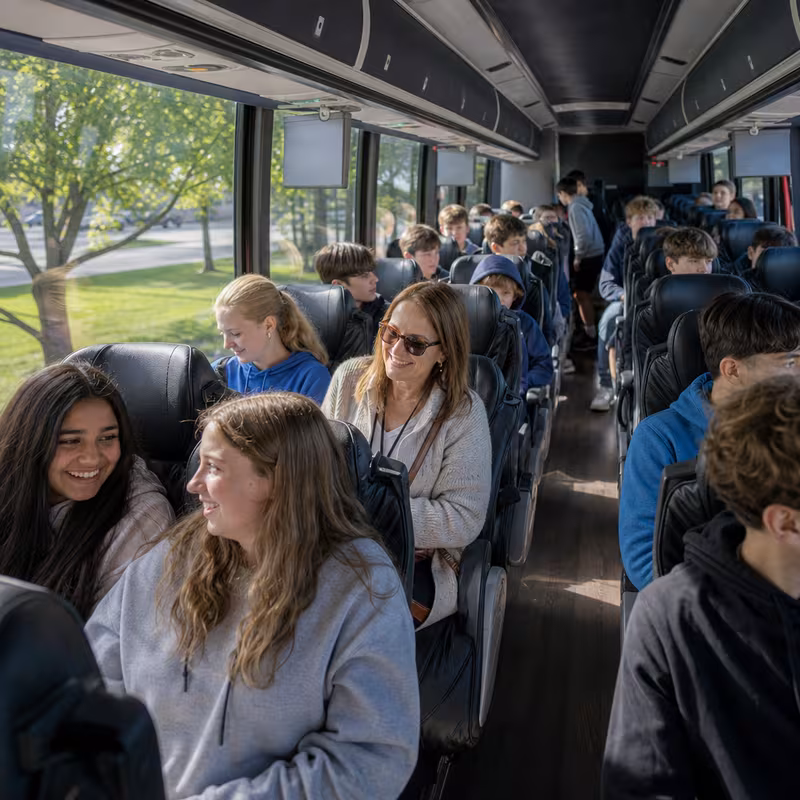 Group boarding a white charter bus for School Transportation transportation in Coral Springs